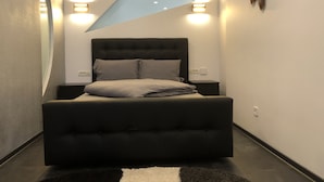 A modern bedroom with a large bed, two bedside tables, and a unique triangular light fixture above the bed.