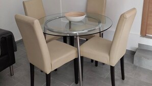 A round glass table with four beige chairs, a white bowl, and a black object on the floor. - charming apartment  (Navas del Rey)