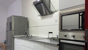 A compact kitchen with a built-in microwave, oven, and stainless steel refrigerator. - charming apartment  (Navas del Rey)