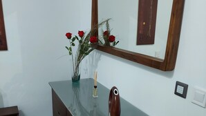 A bathroom with a wooden vanity, a mirror, and a vase with red roses. - charming apartment  (Navas del Rey)