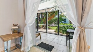 Ein Zimmer mit einem Holztisch, einer Bank und Blick ins Freie durch große Fenster.