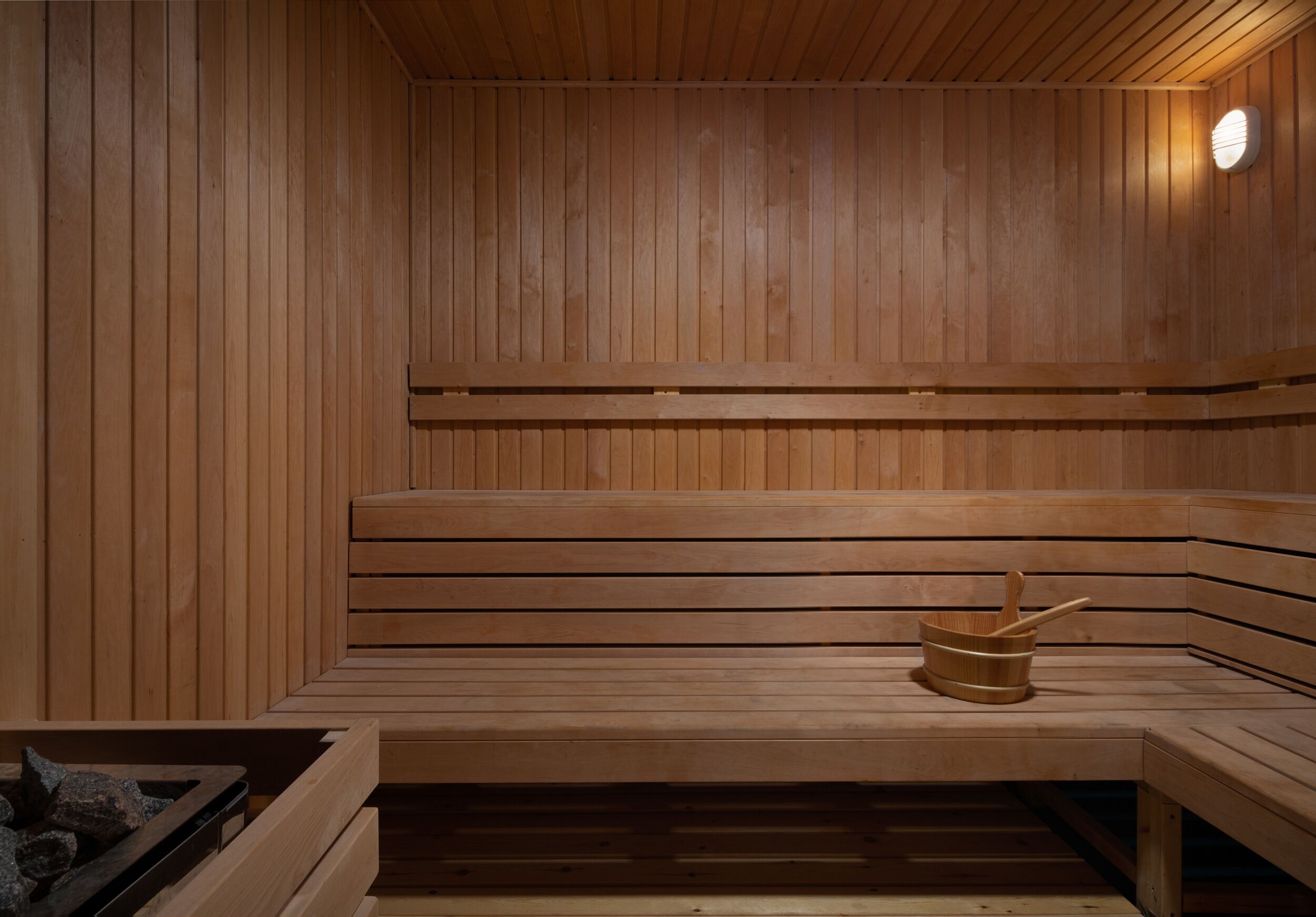 A wooden sauna with benches and a bucket.