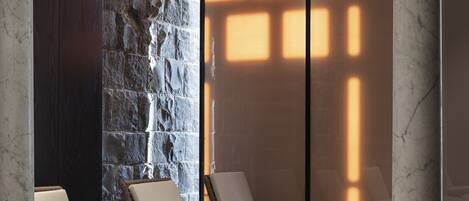 A spa area with lounge chairs, a stone wall, and a patterned floor.