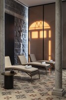 A spa area with lounge chairs, a stone wall, and a patterned floor.