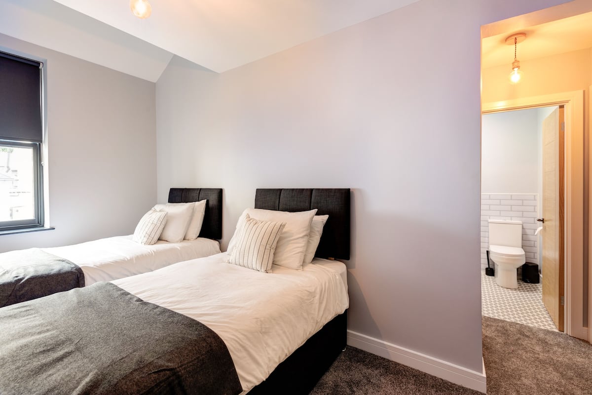 Une chambre avec deux lits, une fenêtre et une vue sur la salle de bain.