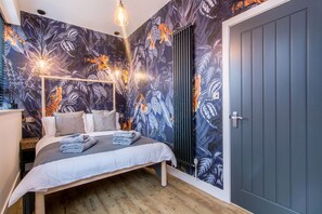 A bedroom with a bed, a radiator, and a wardrobe. - The Brewery Apartments (Stockport)