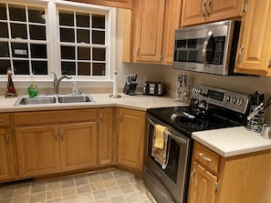 Enjoy cooking in this well-equipped kitchen with a stove, microwave, and toaster, plus ample counter space and a large window.