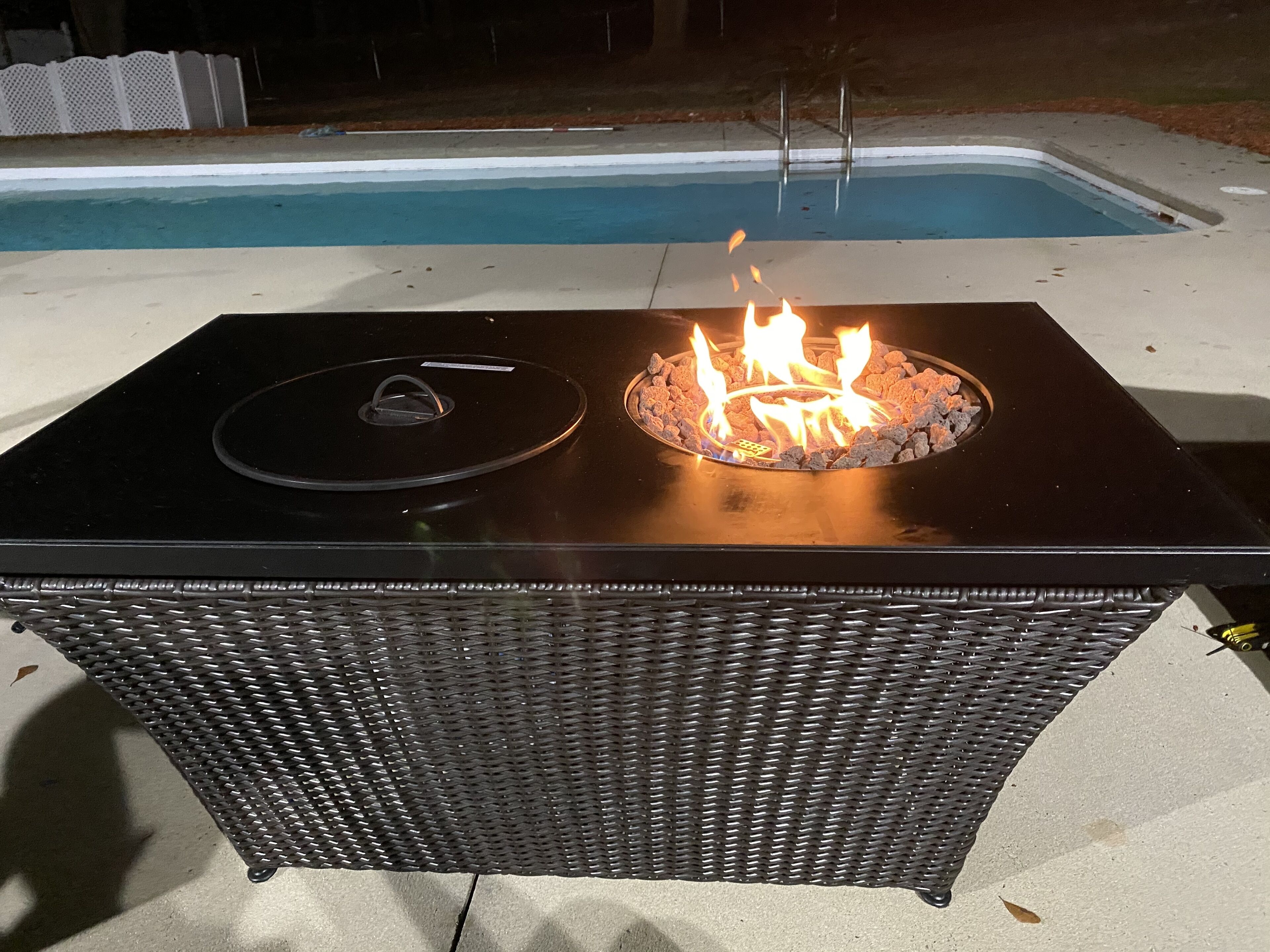 A rectangular outdoor grill with a black top and a fire burning inside.