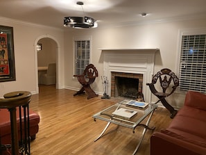 Cozy living room with a traditional fireplace, ornate chairs, and a comfortable sofa.