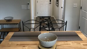 A dining area with a wooden table, a bowl, and a metal chair. There are three pendant lights hanging above the table.