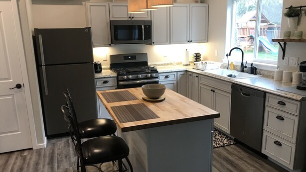A modern kitchen with a central island, stainless steel appliances, and a view of the backyard.