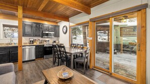 Una cocina con armarios oscuros, un microondas y un comedor con mesa y sillas.