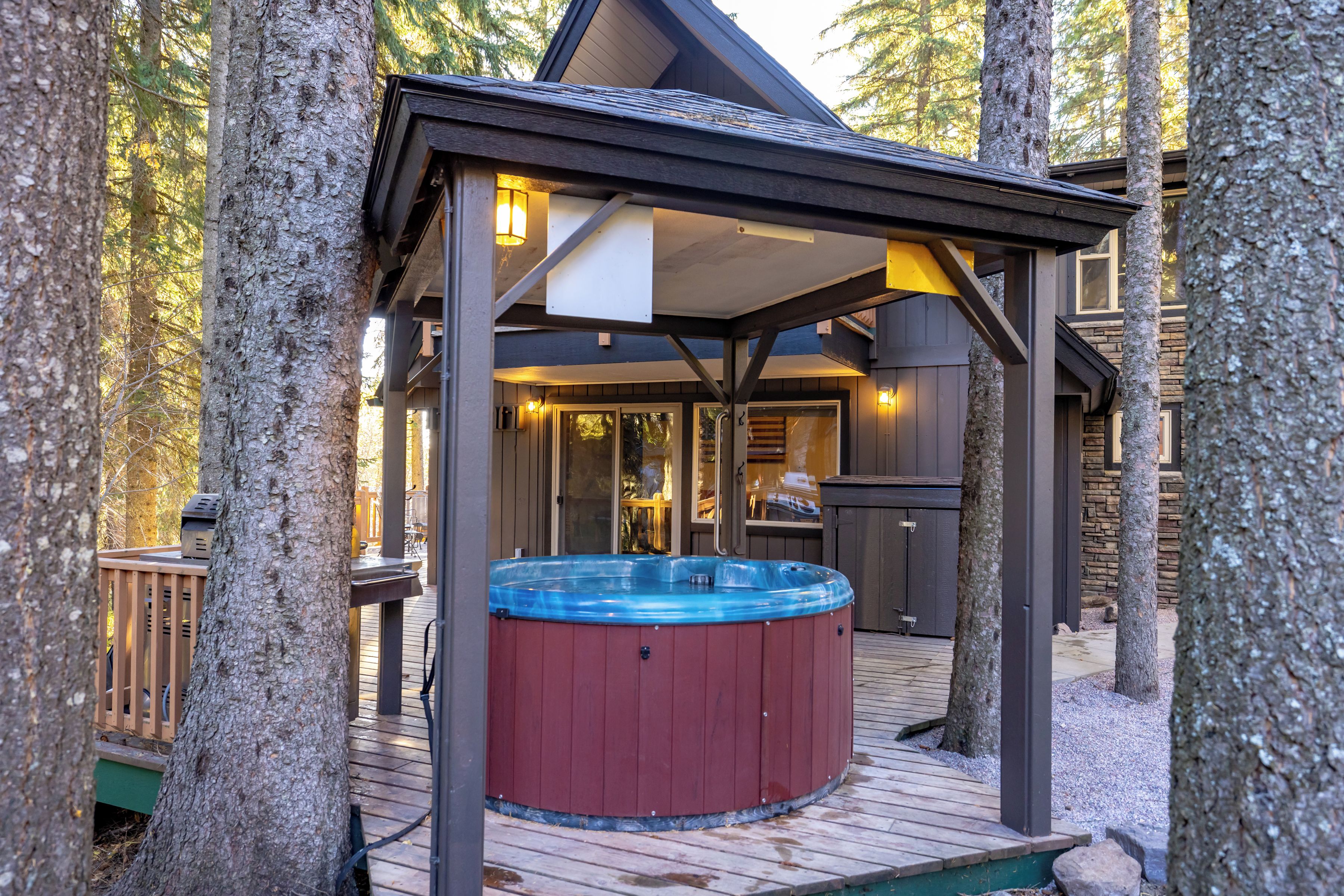 Een hottub op een houten terras, met een overdekte zithoek en een stenen muur op de achtergrond.