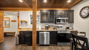 Una cocina moderna con armarios oscuros, electrodomésticos de acero inoxidable y techo de madera.
