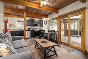 A cozy living room with a sofa, a wooden coffee table, and a dining area with chairs and a table. - Fully remodeled ski condo with private hot tub, close access to ski trail!!! (Whitefish)