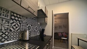 A modern kitchen with patterned backsplash tiles, a stainless steel kettle, and a dark countertop. - -- Love Life -- (Mulhouse)