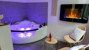 A modern bathroom with a freestanding bathtub, a small round table with a bottle and glass, and two chairs with cushions. - -- Love Life -- (Mulhouse)