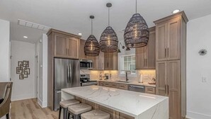 A modern kitchen with a marble island, wooden cabinets, and pendant lighting. - b6 sun and sand, B6 Oceanfront Ocean Lakes (Myrtle Beach)