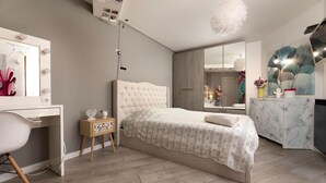 Une chambre à coucher moderne avec un grand lit, une coiffeuse avec un miroir et un bureau avec une chaise.
