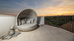Une terrasse sur le toit, dotée d’un espace salon circulaire recouvert de tissu et d’une rambarde en métal.