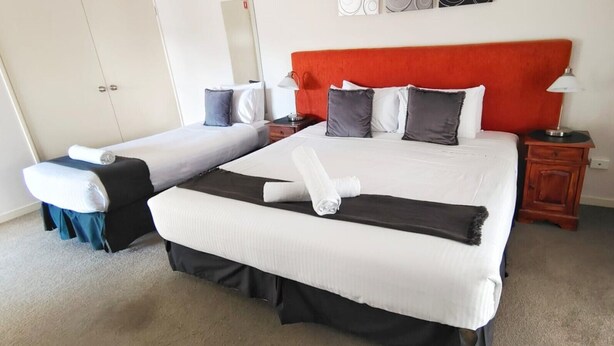 A hotel room with two beds, a red headboard, and a small bedside table with a lamp. - Suite 26 |Town Central | Walk To Cafes | Sleeps 3 (Margaret River)