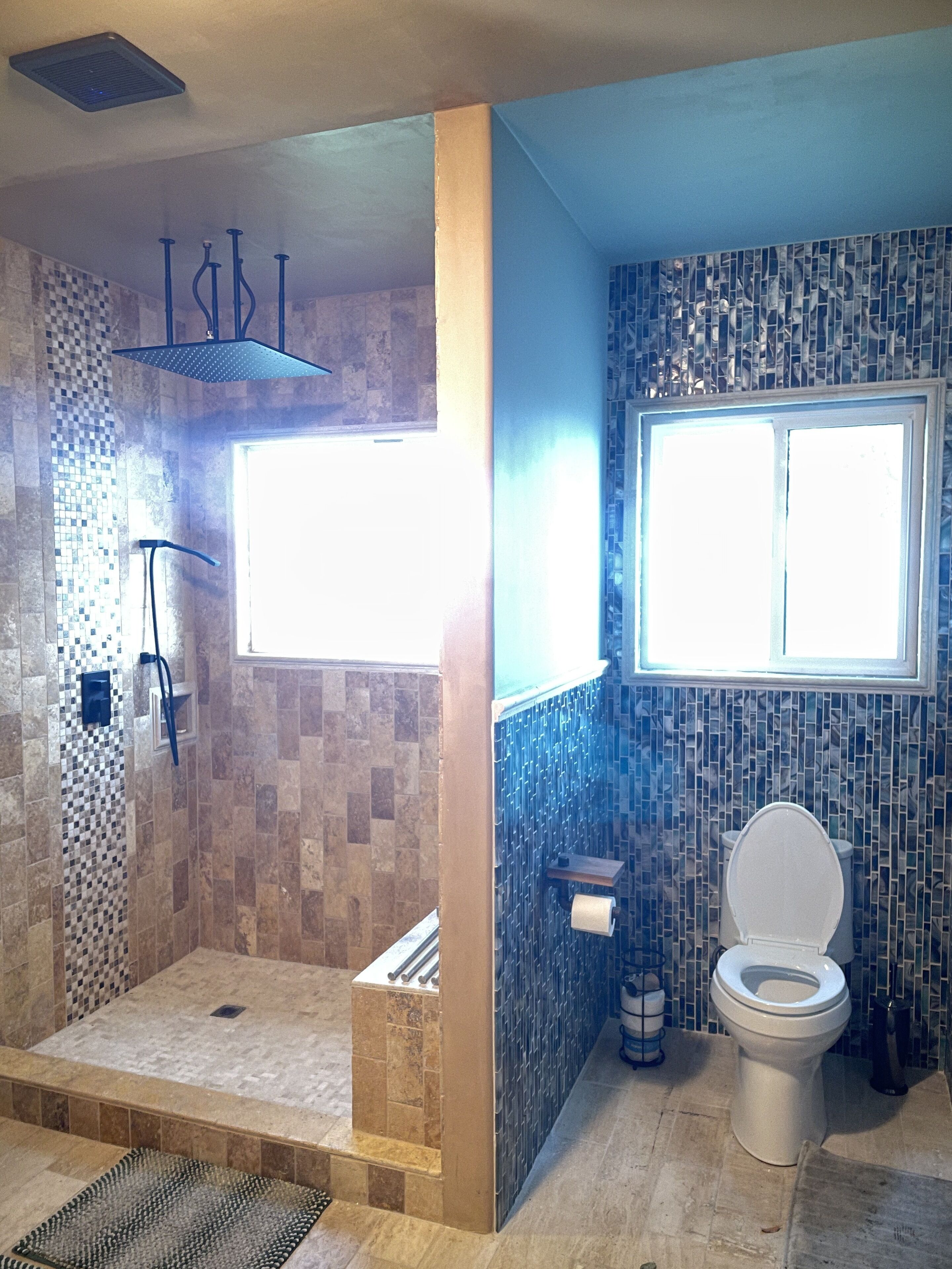 Un baño con ducha, inodoro y ventana.