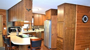Une cuisine avec des meubles de rangement en bois, un réfrigérateur, un four à micro-ondes et un évier.