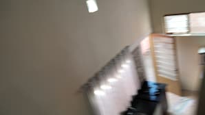 Ein Zimmer mit einem Bett, einem Nachttisch und einem Fenster mit Jalousien.