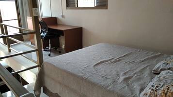 A bedroom with a bed, a desk, and a chair.