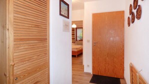 Una puerta de madera con un ventanal pequeño, un cuadro en la pared y un banco de madera al fondo.