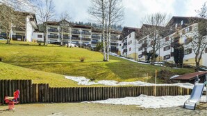 Un barrio residencial con una colina cubierta de césped, un parque infantil y edificios de apartamentos al fondo.