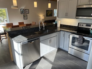 A modern kitchen with a granite countertop, stainless steel appliances, and white cabinetry.