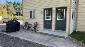 Un bâtiment à deux étages doté d’un porche à l’avant, de deux portes et d’un barbecue couvert.
