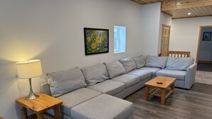 Een moderne woonkamer met een hoekbank, een klein houten tafeltje en een lamp.