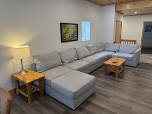 A modern living room with a sectional sofa, a small wooden table, and a lamp.