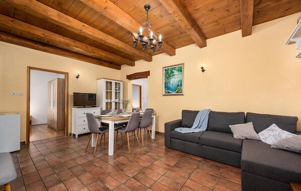 A living room with a dining area, wooden ceiling beams, a TV, and a painting on the wall. - Gorgeous home in Pazin (Pazin)