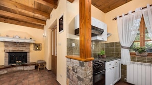 A kitchen with a stone fireplace, wooden beams, and a window with curtains. - Gorgeous home in Pazin (Pazin)