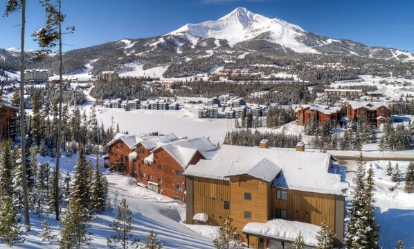 A snow-covered mountain with a ski resort in the background.