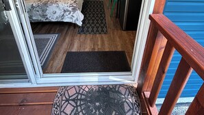 A room with a bed, a desk, a chair, a small table, a potted plant, and a wall mural. - Gabriola Small Suite with Hot Tub (Gabriola)