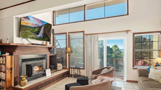 Un salon avec une cheminée, un téléviseur et une grande fenêtre donnant sur un beau paysage.