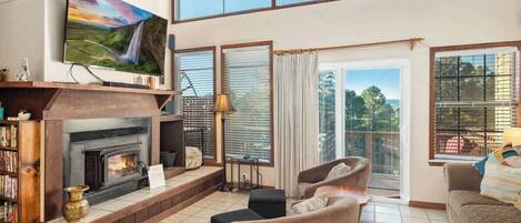 A living room with a fireplace, a television, and a large window with a view.