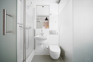 A modern bathroom with a glass shower enclosure, a white sink, and a toilet.