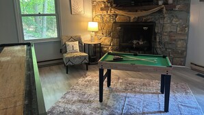 A cozy room with a pool table, a fireplace, a television, and a window with a view of trees. - Base Camp at Hawks nest. Near many mountain activities! (Seven Devils)