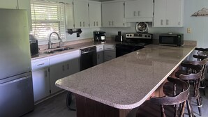 A kitchen with white cabinets, a granite countertop, a stove, a microwave, and a coffee maker. - Base Camp at Hawks nest. Near many mountain activities! (Seven Devils)