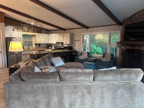 A living room with a sofa, chairs, a fireplace, and a kitchen in the background. - Base Camp at Hawks nest. Near many mountain activities! (Seven Devils)