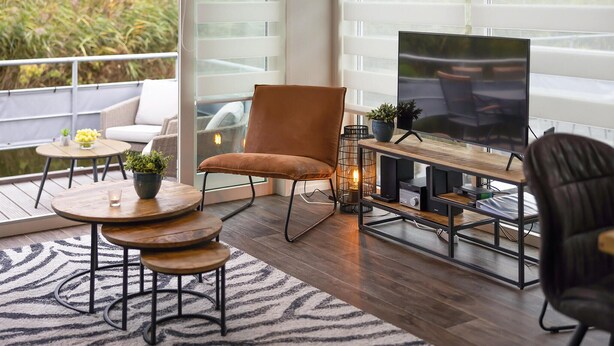 Uma sala de estar moderna com uma televisão grande, assentos confortáveis e vista para o verde lá fora.