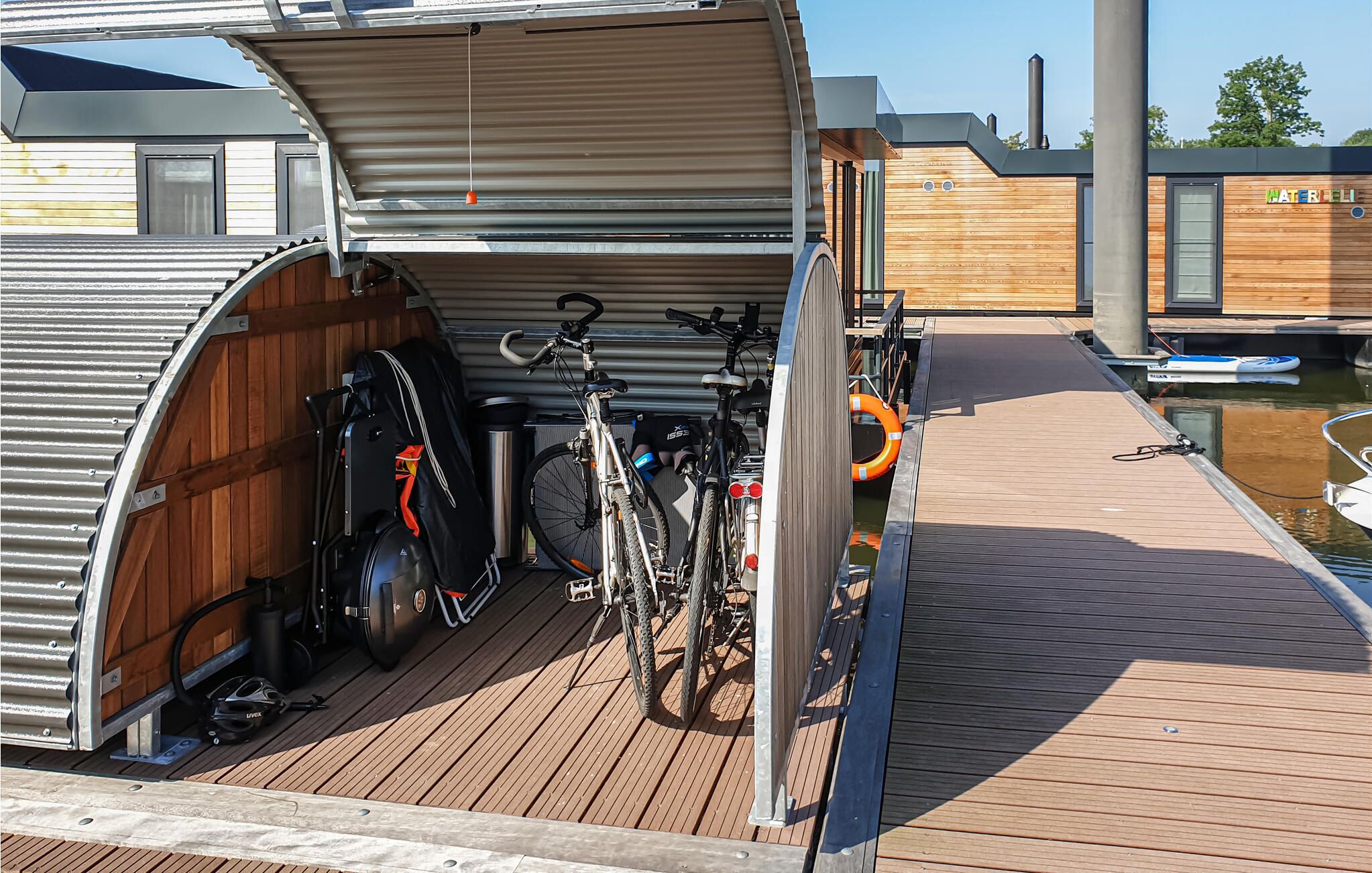 A covered bicycle storage area with a wooden deck leading to a dock.