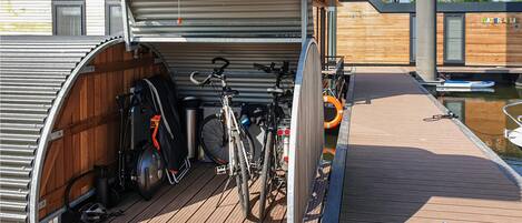 A covered bicycle storage area with a wooden deck leading to a dock.