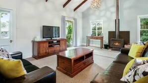 Uma sala de estar espaçosa com lareira, aparador de madeira e uma janela grande.
