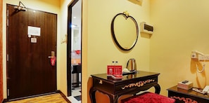 A hotel room with a wooden door, a mirror, a bedside table with a red towel, a bedside lamp, and a telephone. - Hotel 1888 Collection (Singapore)